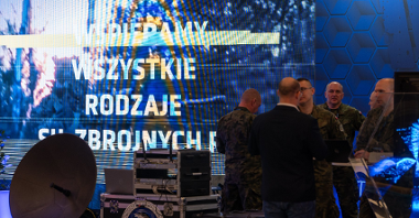 Na zdjęciu ludzie przed ekranem, na nim napis: wspieramy wszystkie rodzaje sił zbrojnych RP