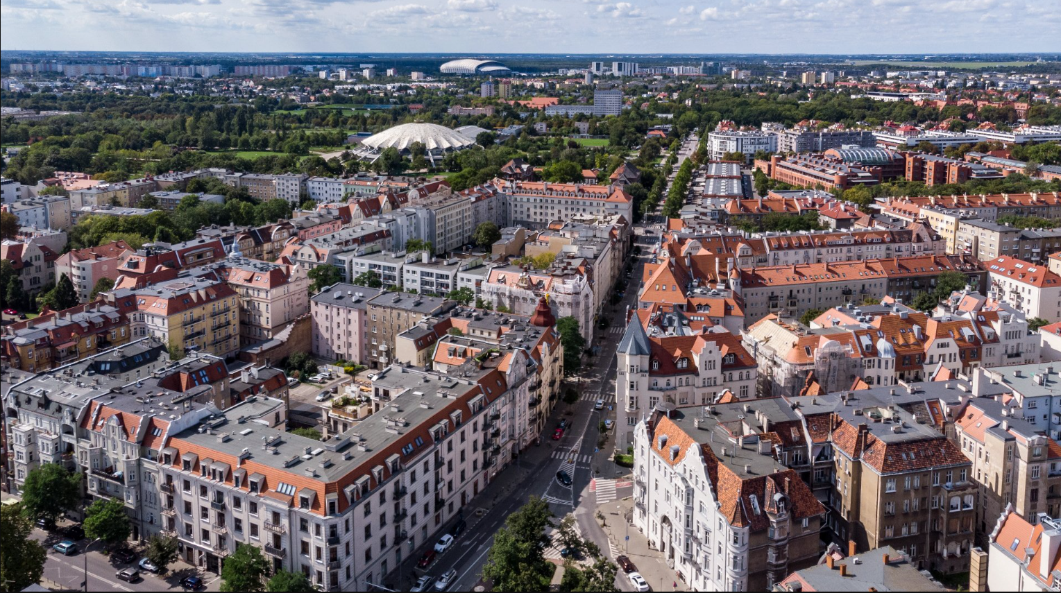 Na zdjęciu panorama Poznania z lotu ptaka, widać kamienice, w tle Arenę - grafika artykułu